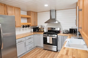 Une cuisine moderne dotée d’appareils électroménagers en acier inoxydable, de meubles en bois et d’un four encastré.