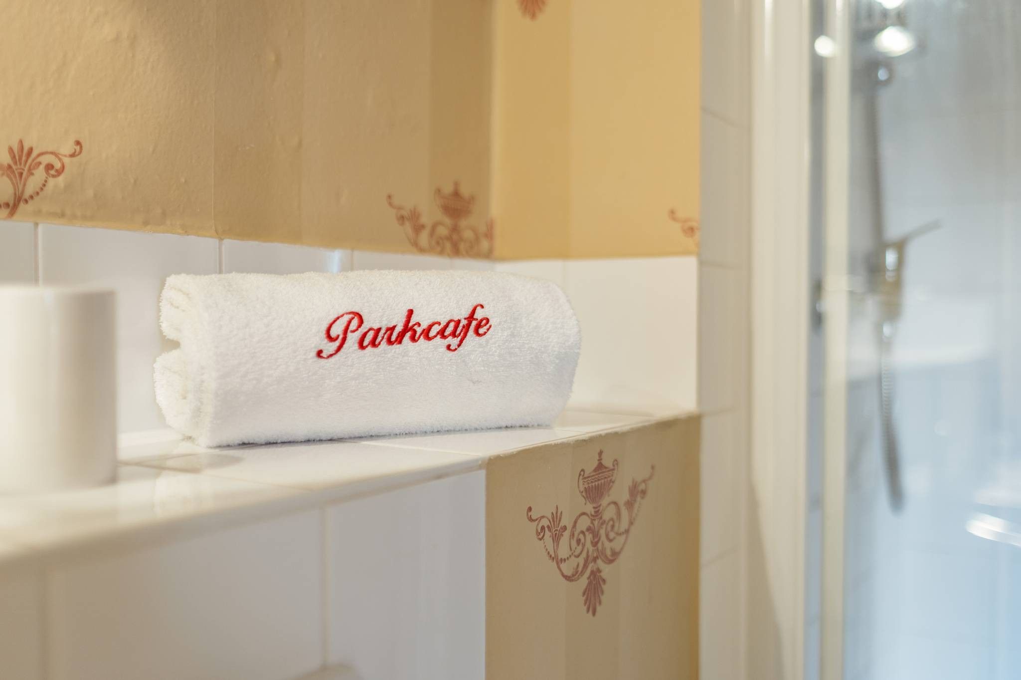 A bathroom with a white towel on a shelf, a toilet, and a shower area.