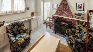 A living room with a fireplace, two floral-patterned armchairs, a wooden coffee table, and a television.