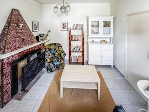 A living room with a fireplace, a bookshelf, a white cabinet, and a coffee table.