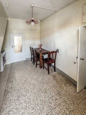 A dining area with a table and chairs, a ceiling fan, a white door, and a tiled floor.