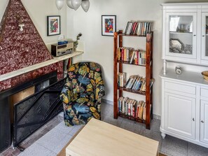 A living room with a fireplace, a bookshelf, and a floral armchair.