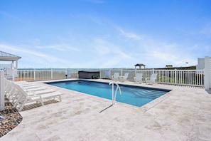 Ein Pool mit Meerblick, umgeben von einem weißen Zaun und Liegestühlen.
