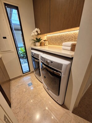 A compact kitchen with a built-in oven, a washing machine, and a small sink. - Stunning Ocean view -Wailea Point 2bd/2b Condo (Wailea)