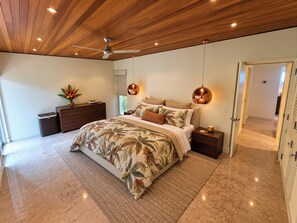 Ein Schlafzimmer mit einem großen Bett, Holzboden und zwei Pendelleuchten.