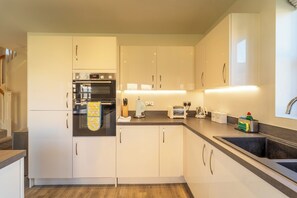 Une cuisine moderne avec des meubles blancs, un four encastré, un grille-pain et un évier.