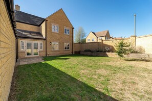 A residential property with a stone facade, a grassy yard, and a paved driveway. - Modern Home Near Blenheim Palace & The Cotswolds - Pass the Keys (Long Hanborough)