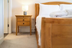 A bedroom with a wooden bed, a nightstand with a lamp, and a carpeted floor. - Modern Home Near Blenheim Palace & The Cotswolds - Pass the Keys (Long Hanborough)