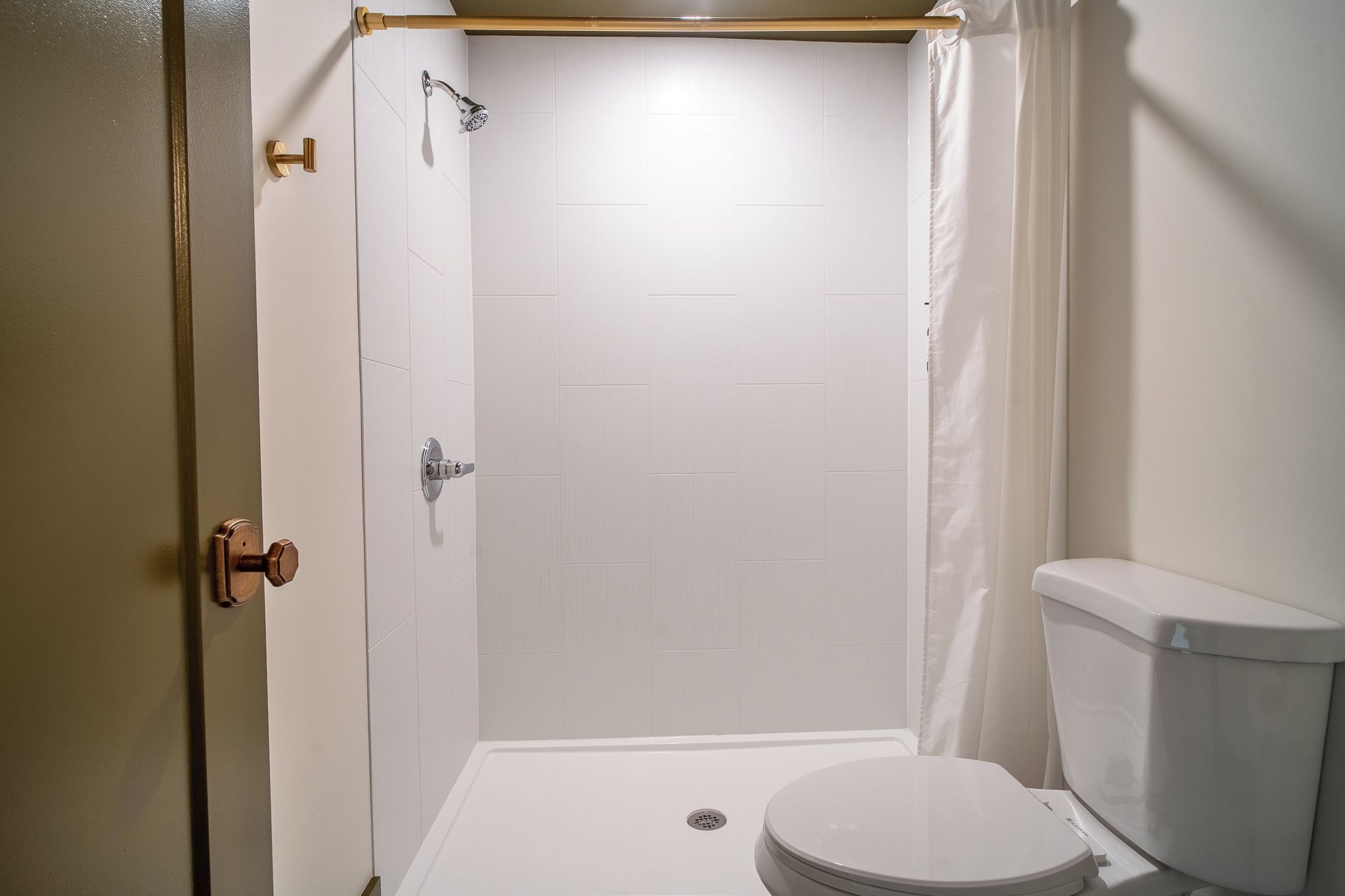 A bathroom with a shower, toilet, and a door.