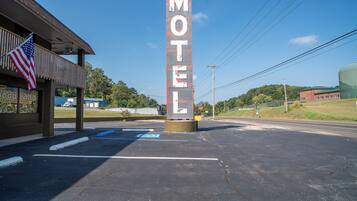 A motel with a prominent vertical sign, a parking lot with marked spaces, and a building with a sign that reads 'Woodland Parkview Motel'.