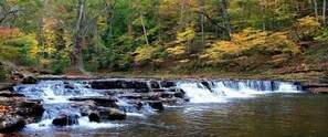 A waterfall in a forested area with trees in autumn colors.