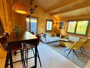 A wooden interior with a dining table, chairs, a sofa, and a coffee table. - Enjoy peace and quiet, nature, and comfort in this cozy vacation home. (Waarland)