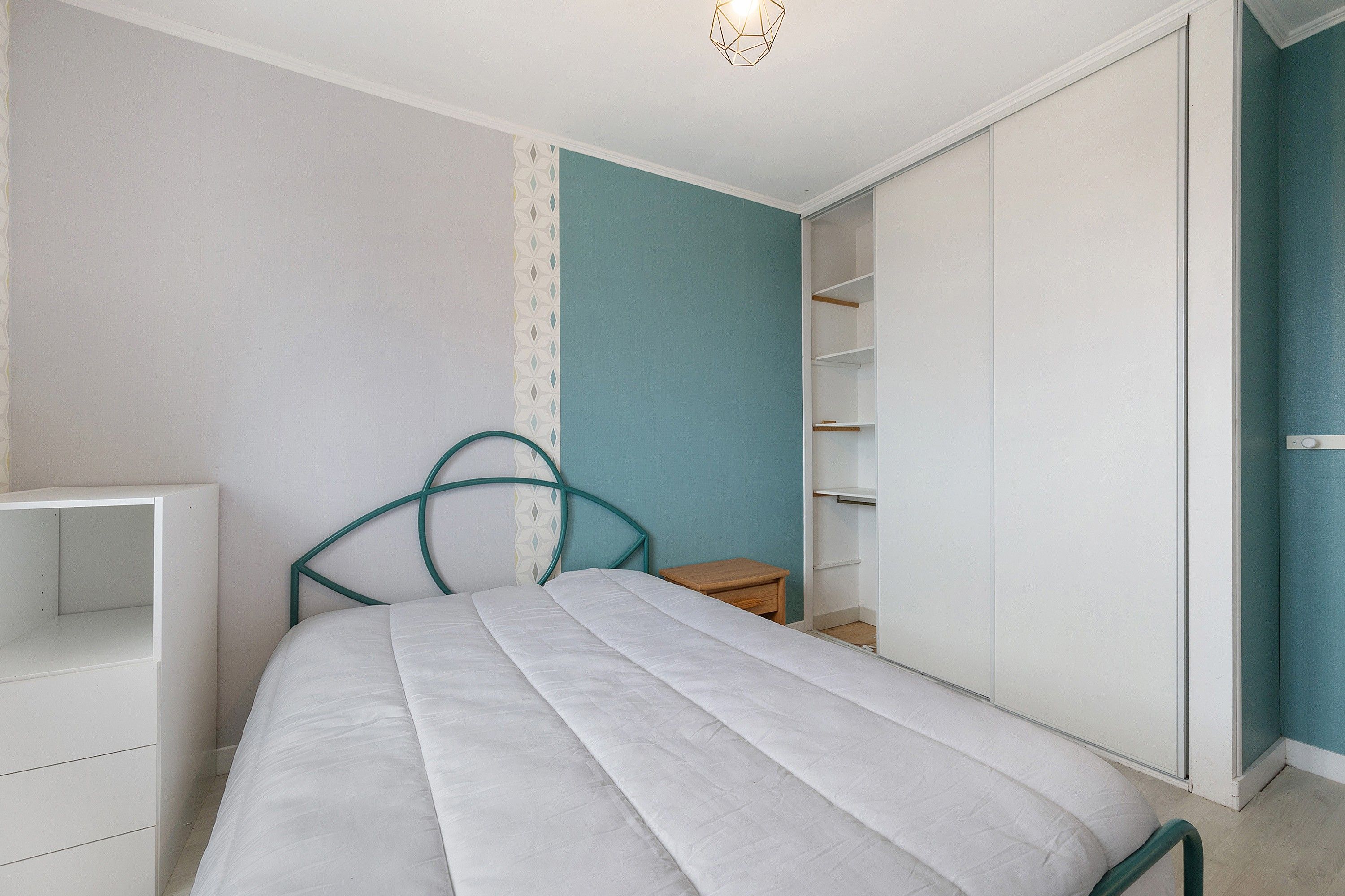 Ein Schlafzimmer mit einem Bett, einem Kleiderschrank und einem Nachttisch.