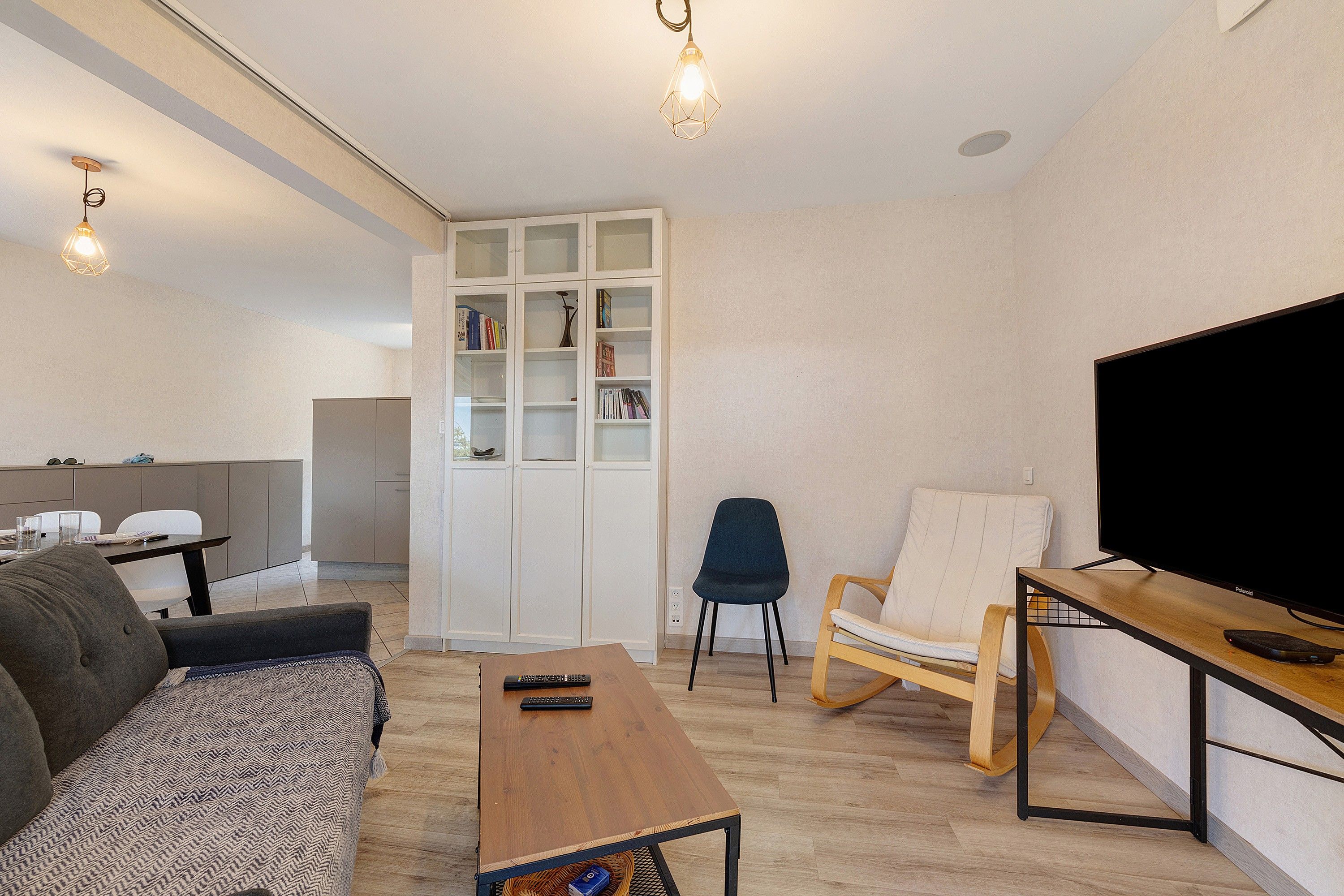 A modern living room with a sofa, a coffee table, a TV stand, and a bookshelf.