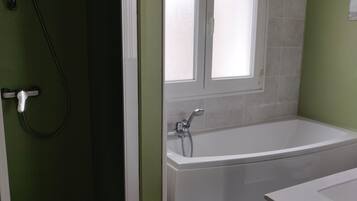 Un baño con bañera, ducha y ventana.