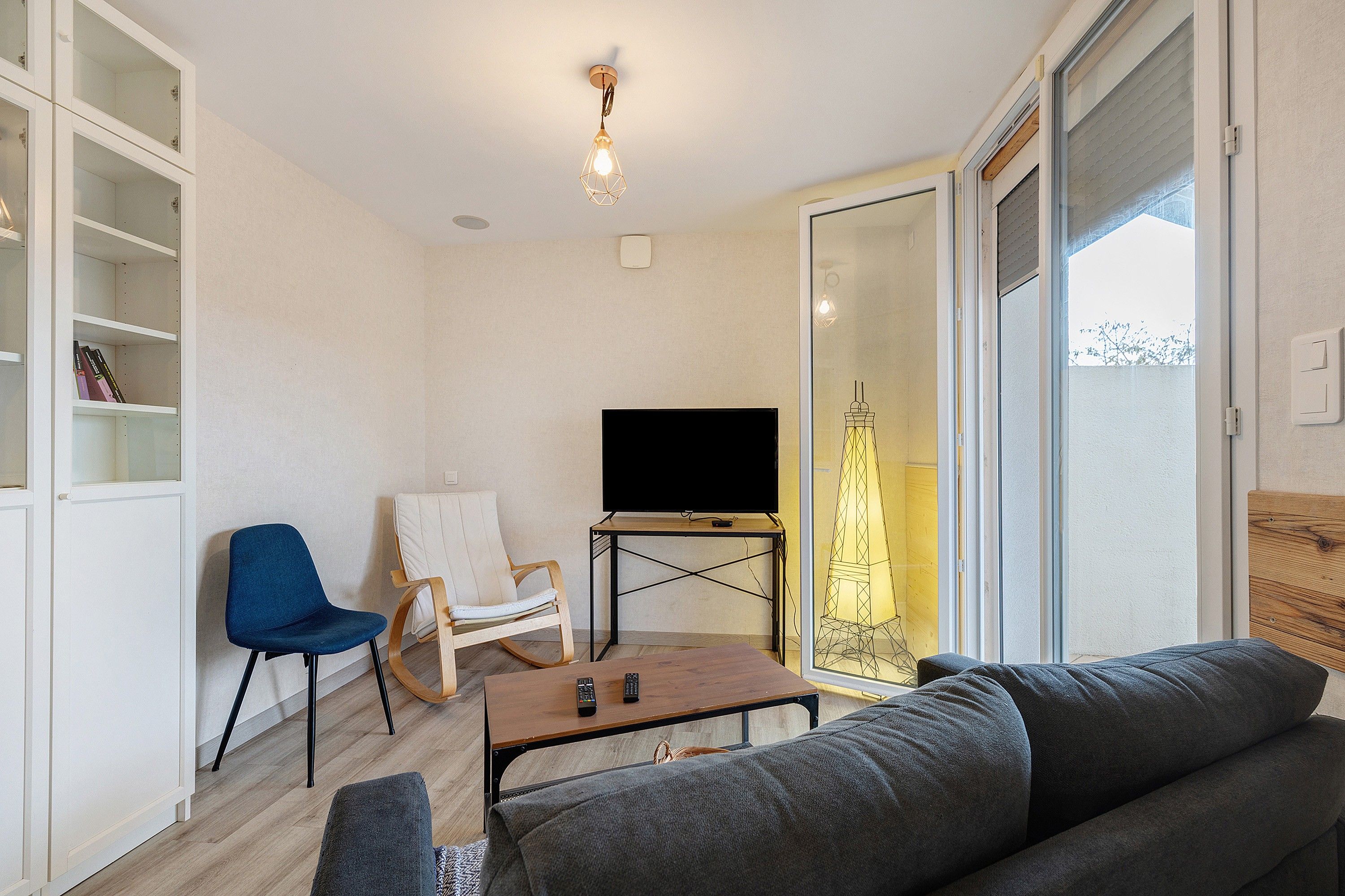 A living room with a sofa, a chair, a coffee table, a TV, and a bookshelf.