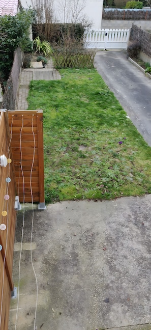 Une cour résidentielle avec une clôture en bois, une allée pavée et une pelouse.