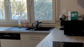A modern kitchen with a built-in dishwasher, a toaster, and a window overlooking a garden.