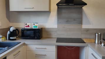 A compact kitchen with a microwave, coffee maker, and a toaster.