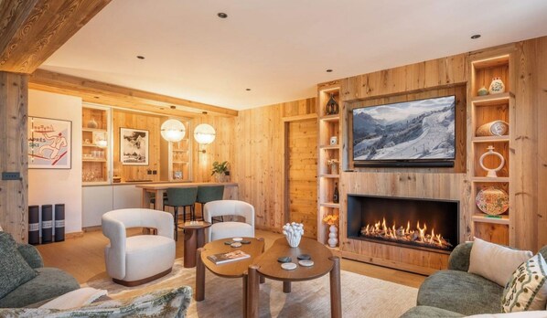 Ein gemütliches Wohnzimmer mit Kamin, Holzwänden, einem Fernseher und einem Essbereich mit Stühlen und einem Tisch.