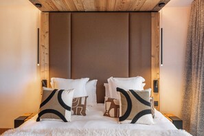 Ein Schlafzimmer mit einem großen Bett, zwei Nachttischen, einem Holzkopfteil und einem flauschigen weißen Teppich.