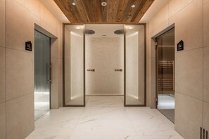 En moderne elevator med glasdøre, træloft og en marmorgulv.
