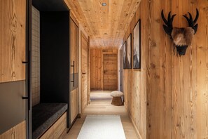 A wooden interior hallway with a bench, a rug, and a mounted animal head on the wall. - Quercus – Ski-in/Out | Fireplace | Views | Méribel (Les Allues)