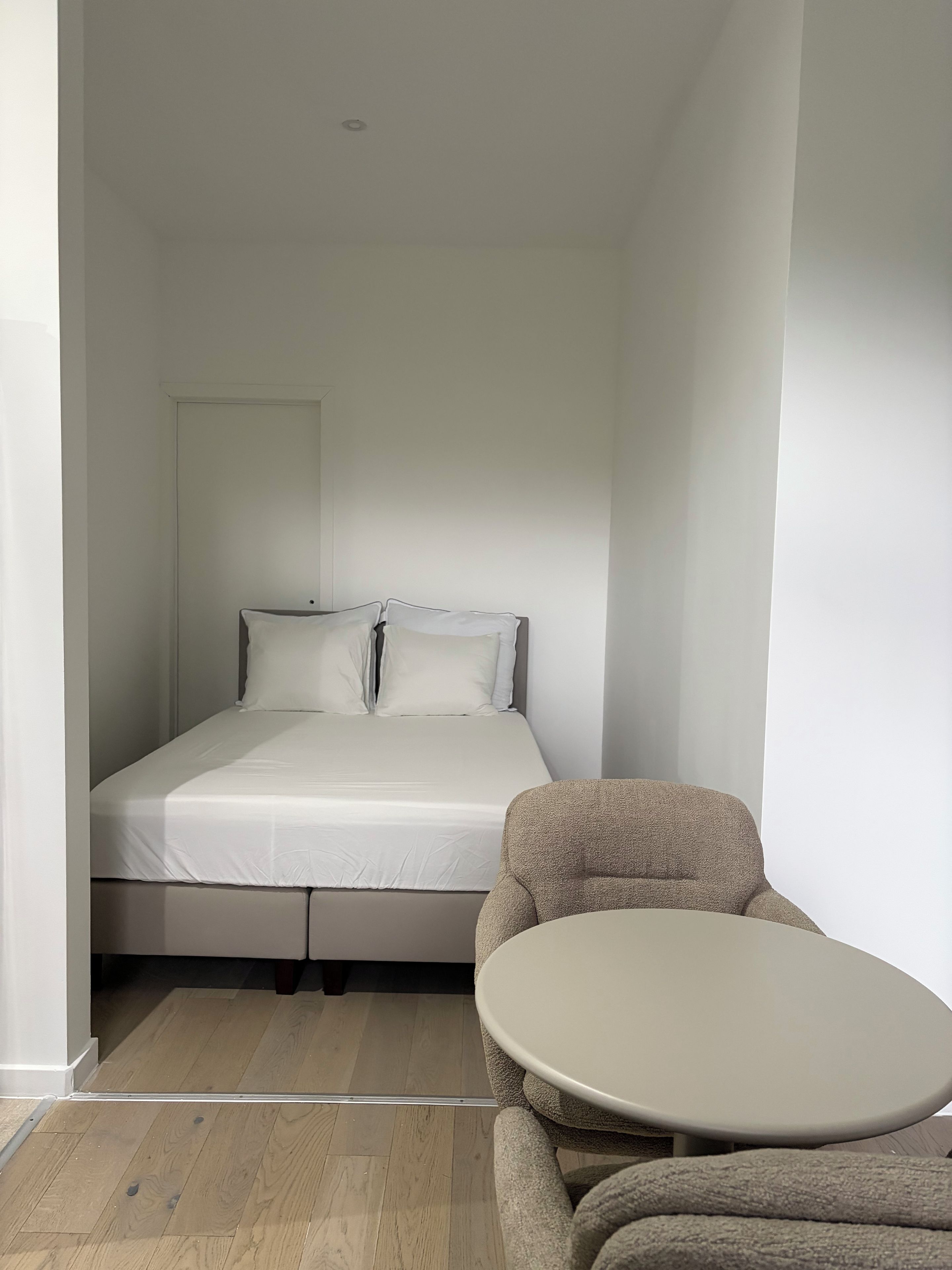 Une petite pièce, de taille modeste, comprenant un lit, une table ronde et une chaise.