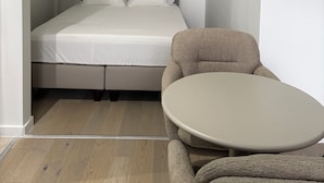 Una habitación pequeña y funcional con una cama, una mesa redonda y una silla.