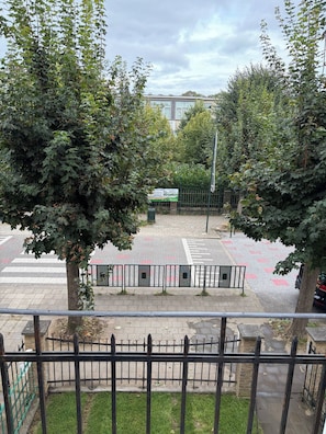 Een uitzicht op een parkeerplaats met een groen bord, een zebrapad en een metalen hek.