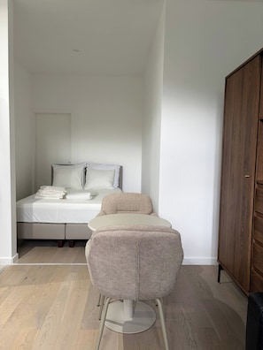 Een slaapkamer met een bed, een klein rond tafeltje en een kledingkast.