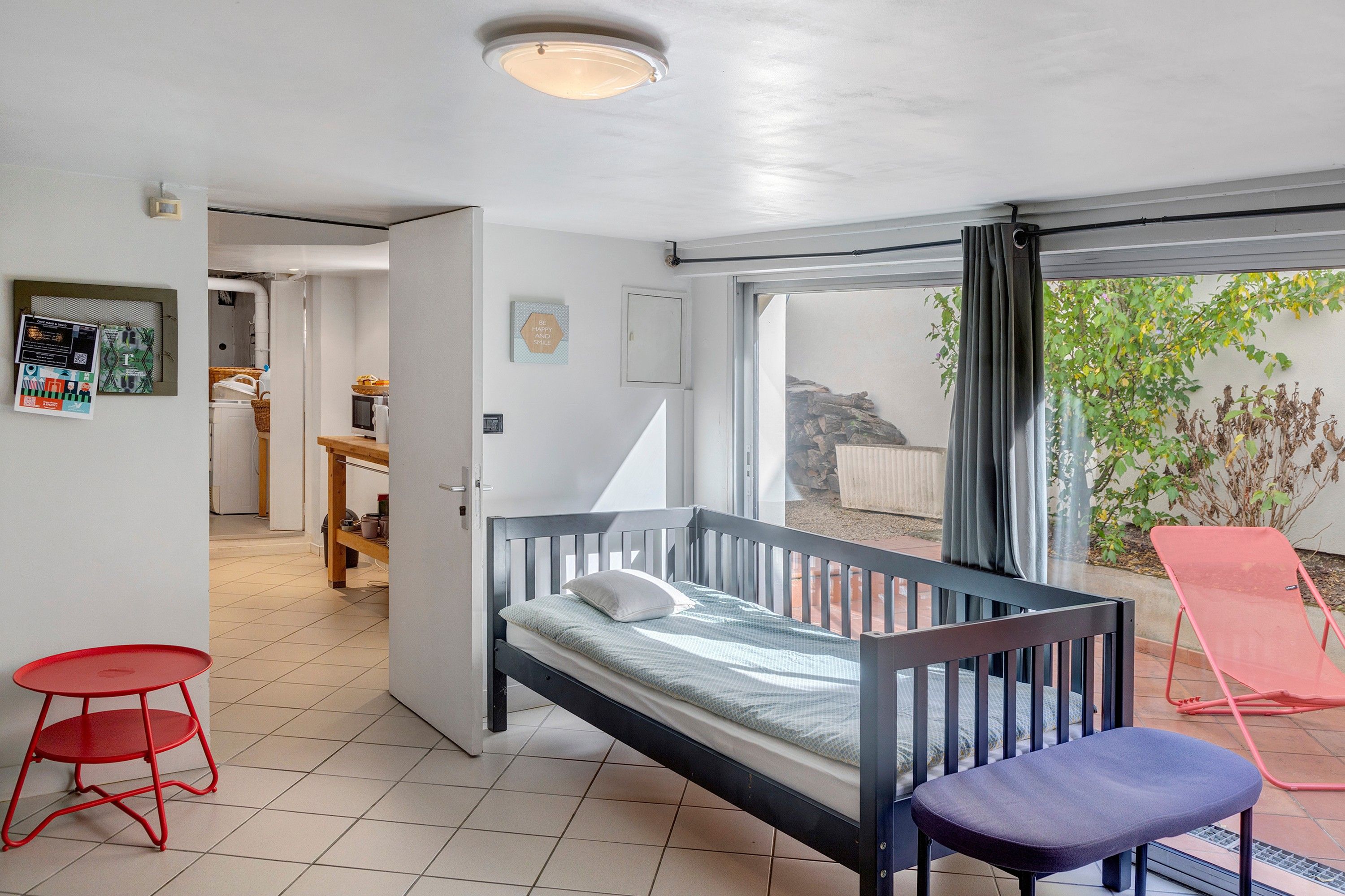 Een slaapkamer met een bed, een rode stoel, een blauwe stoel, een kleine tafel en uitzicht op het omliggende gebied.