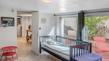 Een slaapkamer met een bed, een rode stoel, een blauwe stoel, een kleine tafel en uitzicht op het omliggende gebied.