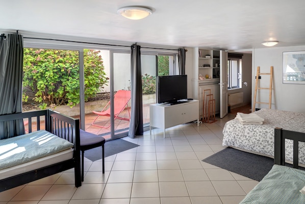 A spacious living area with a sofa, a TV, and a dining table.