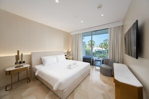 A modern hotel room with a large bed, a seating area with a view, and a flat-screen TV mounted on the wall. - Modern 2BR Gem | Prime Palm Jumeirah Location (Dubai)