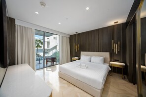 Een moderne hotelkamer met een groot bed, een bureau en een balkon met uitzicht op de stad.
