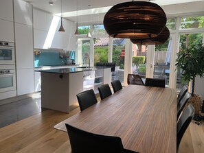 A modern kitchen with white cabinets, a central island, and a dining area with a wooden table and black chairs.