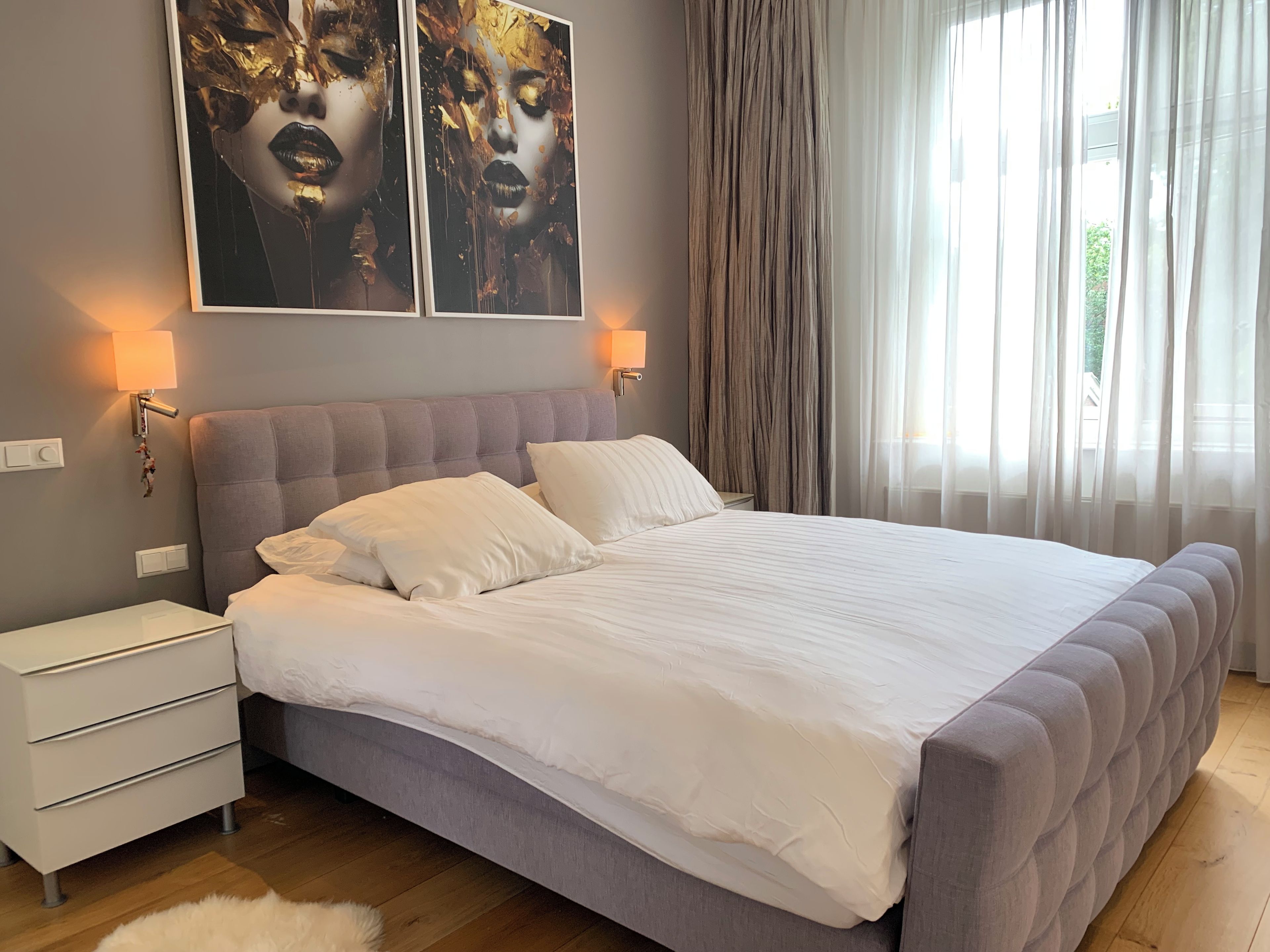 Un dormitorio con una cama grande, mesitas de noche y un ventanal con cortinas.