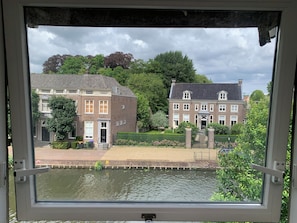 Blick durch ein Fenster auf einen Kanal mit Gebäuden auf der anderen Seite.