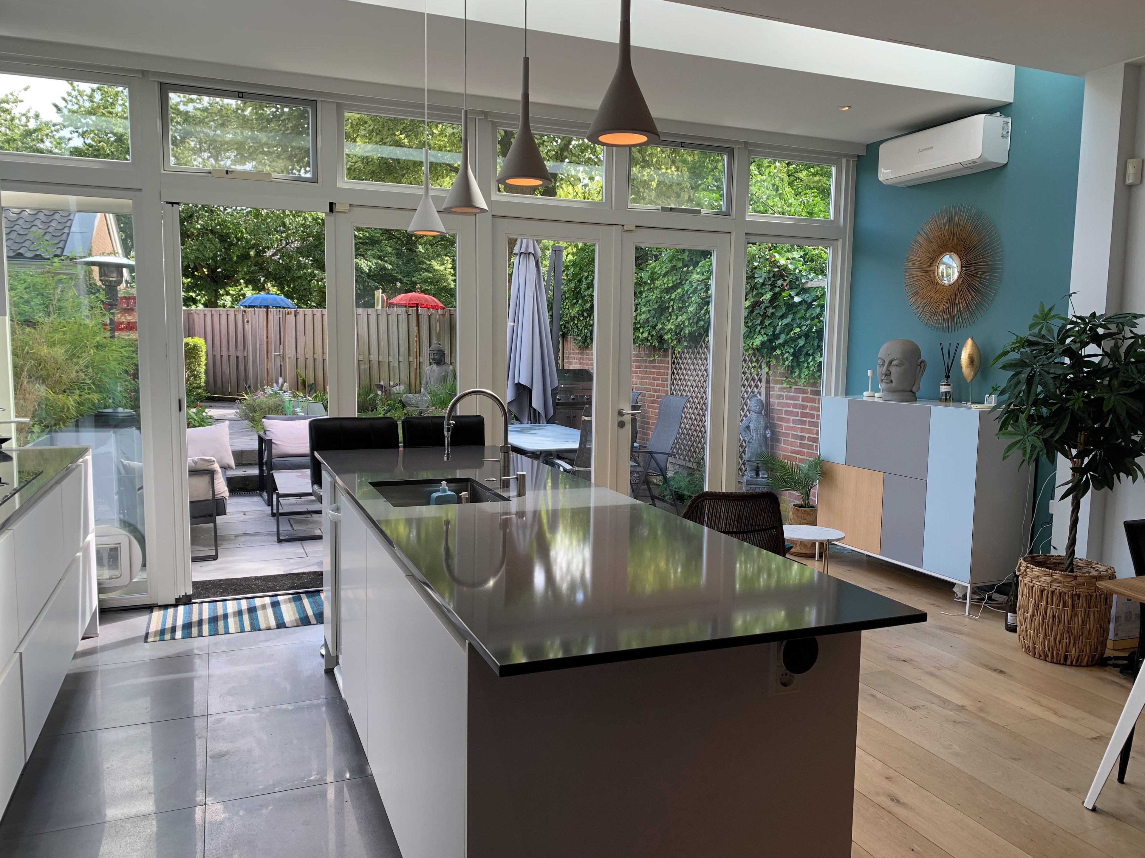 Una cocina moderna con una isla central, ventanas amplias y vista al jardín.