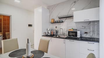 Una cocina moderna con salpicadero de mármol, microondas integrado y cafetera.
