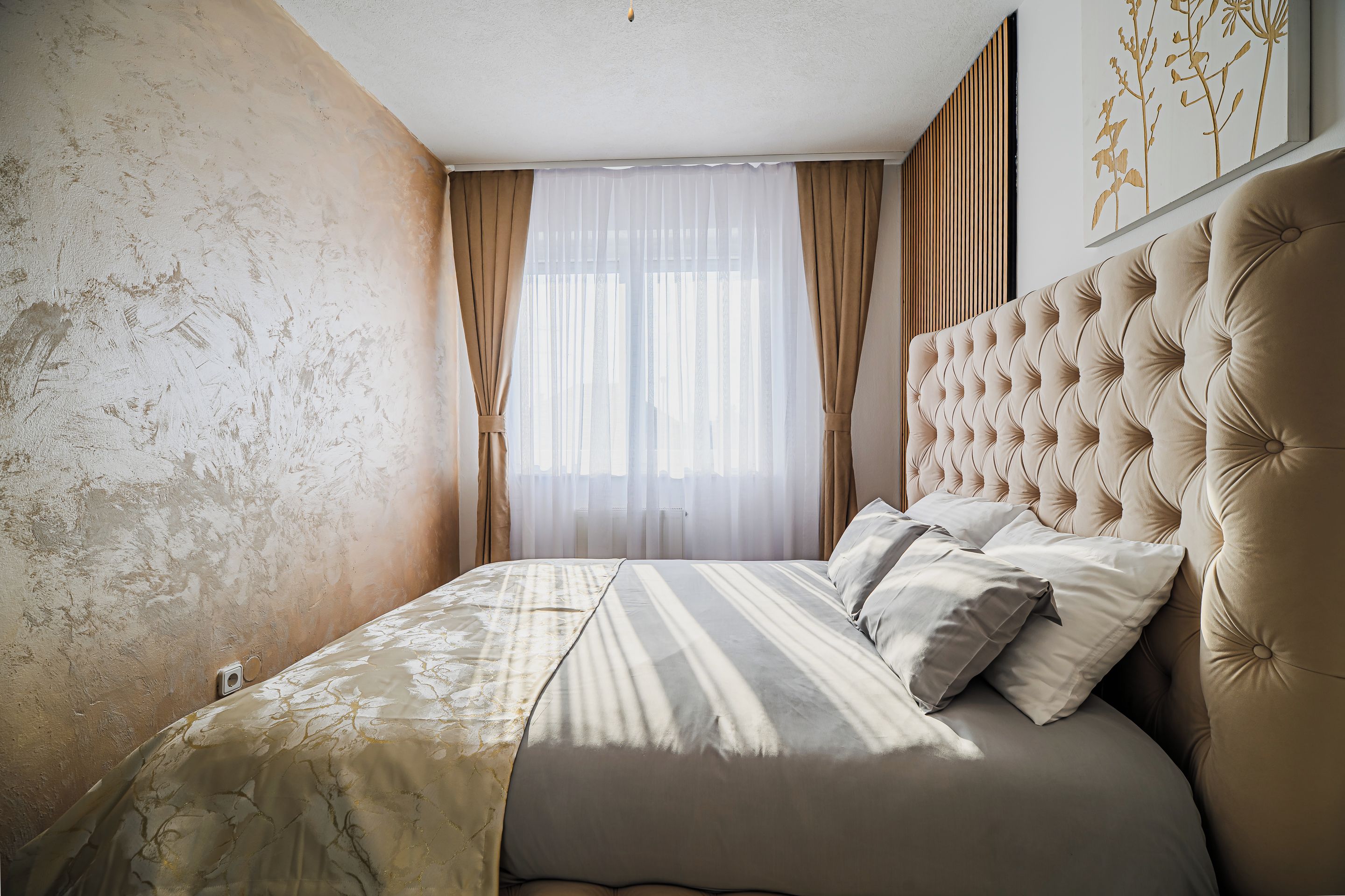 Un dormitorio con una cama grande, cabecera y ventana con cortinas.