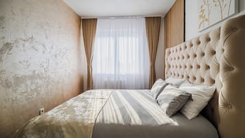 Un dormitorio con una cama grande, cabecera y ventana con cortinas.