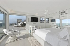 Ein modernes Hotelzimmer mit einem großen Bett, einem Flachbildfernseher und Blick aufs Meer.