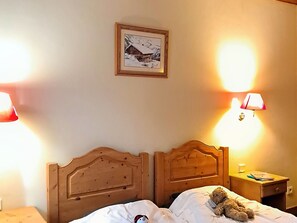 A bedroom with two wooden beds, a nightstand with a lamp, and a framed picture on the wall. - 3-room apartment at the foot of slopes, terrace, 6 pers (Les Deux Alpes)