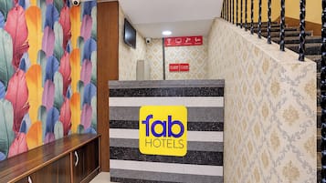 A hotel reception area with a colorful abstract wall, a sign for 'fab hotels', and a staircase with a patterned railing.
