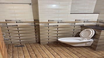 Ein Badezimmer mit Toilette, Holzboden und dekorativen Fliesen.