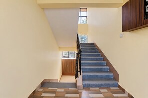 Una escalera de madera que conduce a una plataforma con una puerta y un ventanal.
