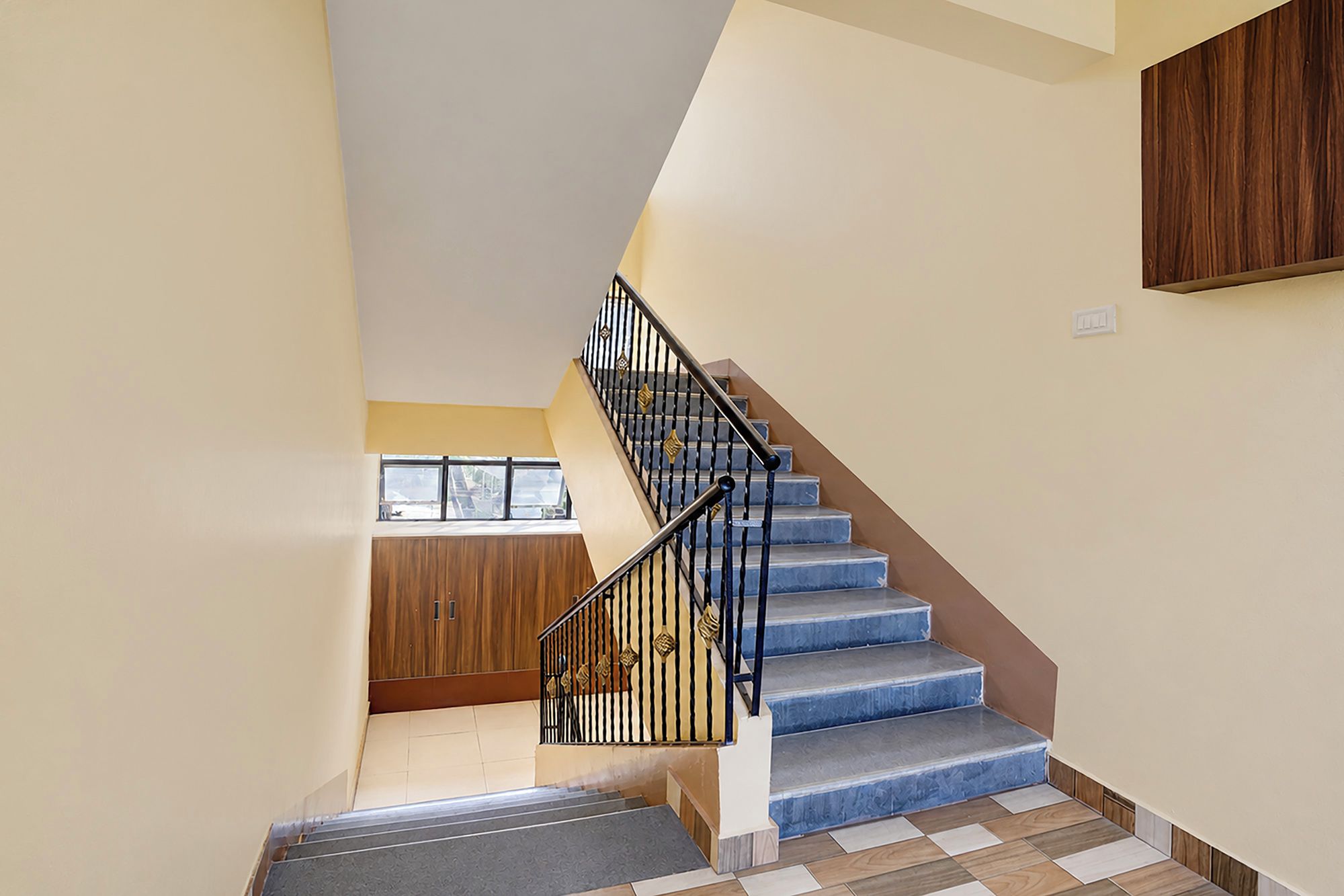 A staircase with a black railing and blue steps leading to a landing.
