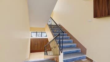 A staircase with a black railing and blue steps leading to a landing.